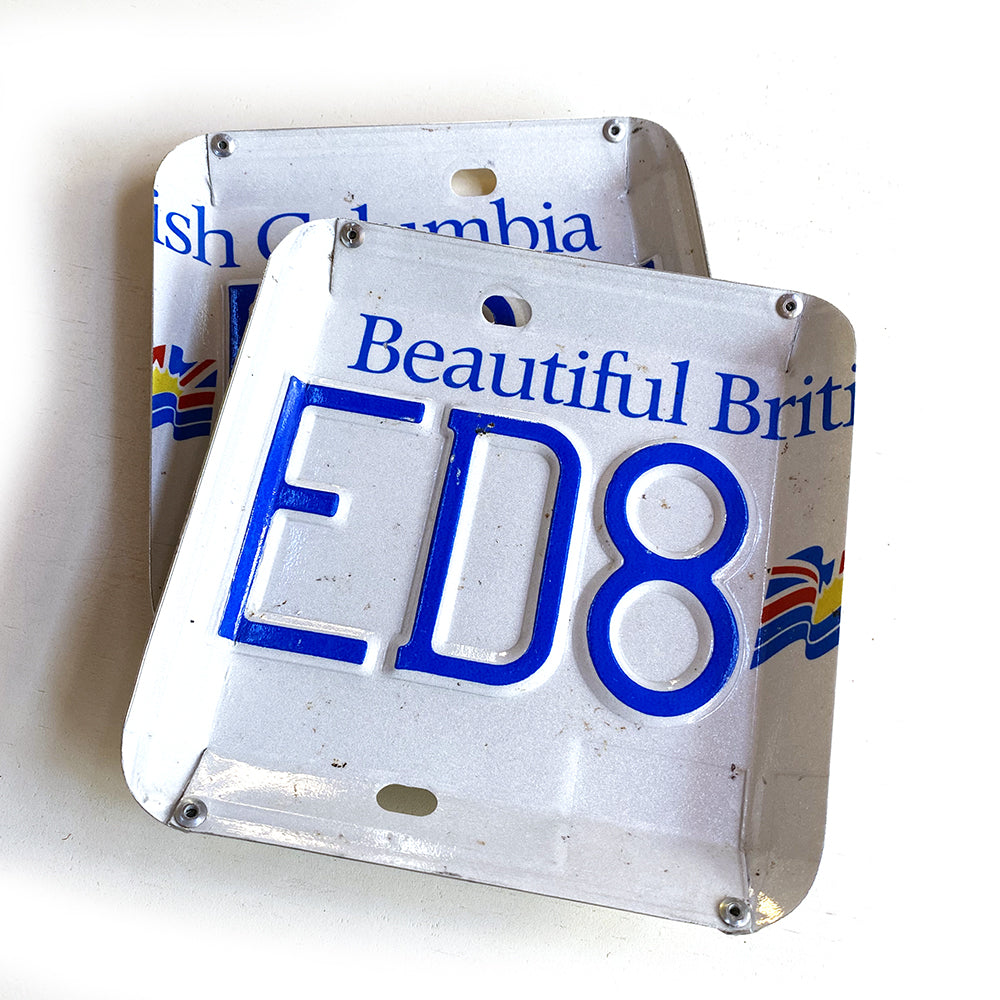 Square shaped catch all tray made from a recycled licence plate. Edges are bent and riveted together on corners to form a bowl shape.