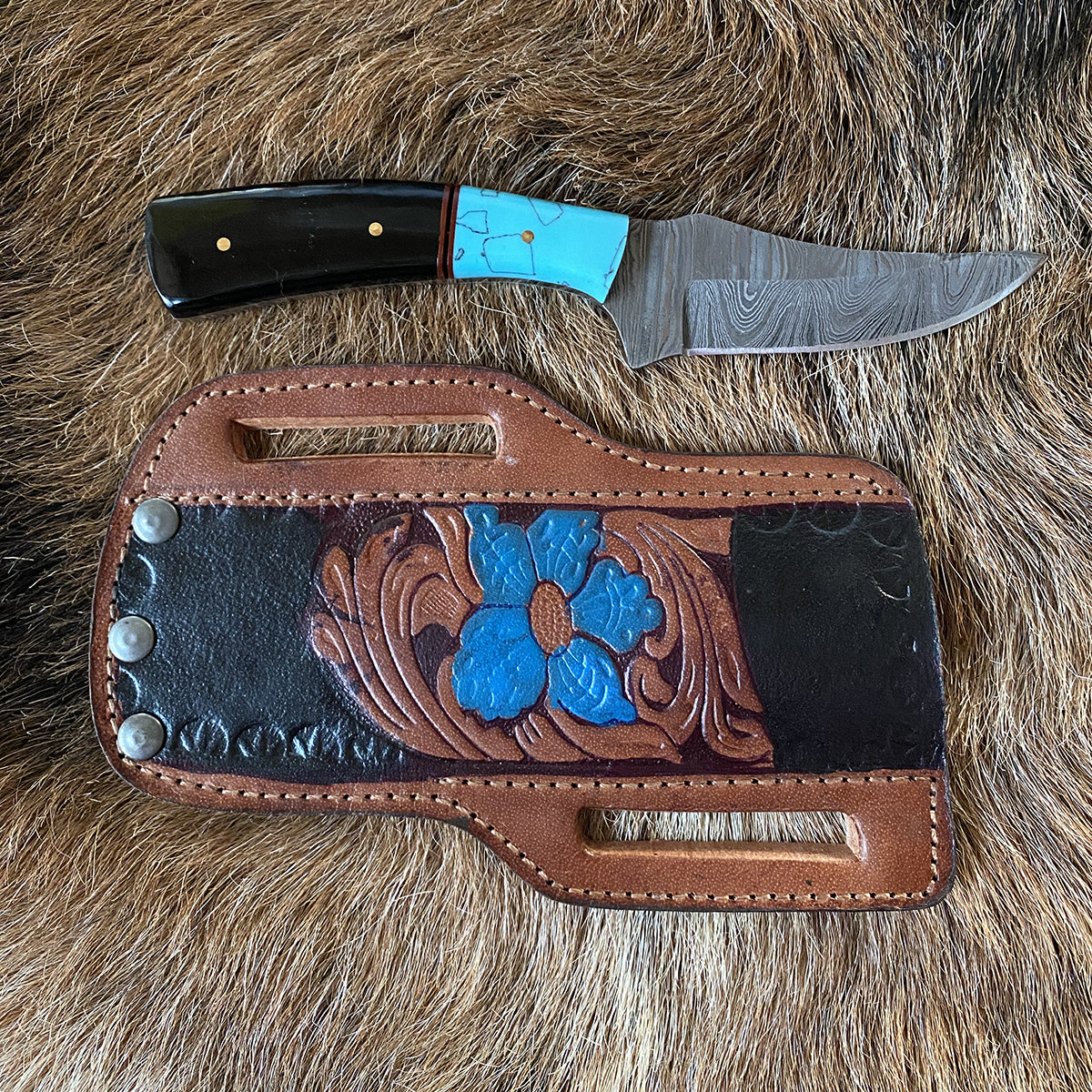 hunting knife featuring handcrafted 3.25" Damascus steel fixed blade, resin handle with brass pins and detail displayed on fur with leather sheath