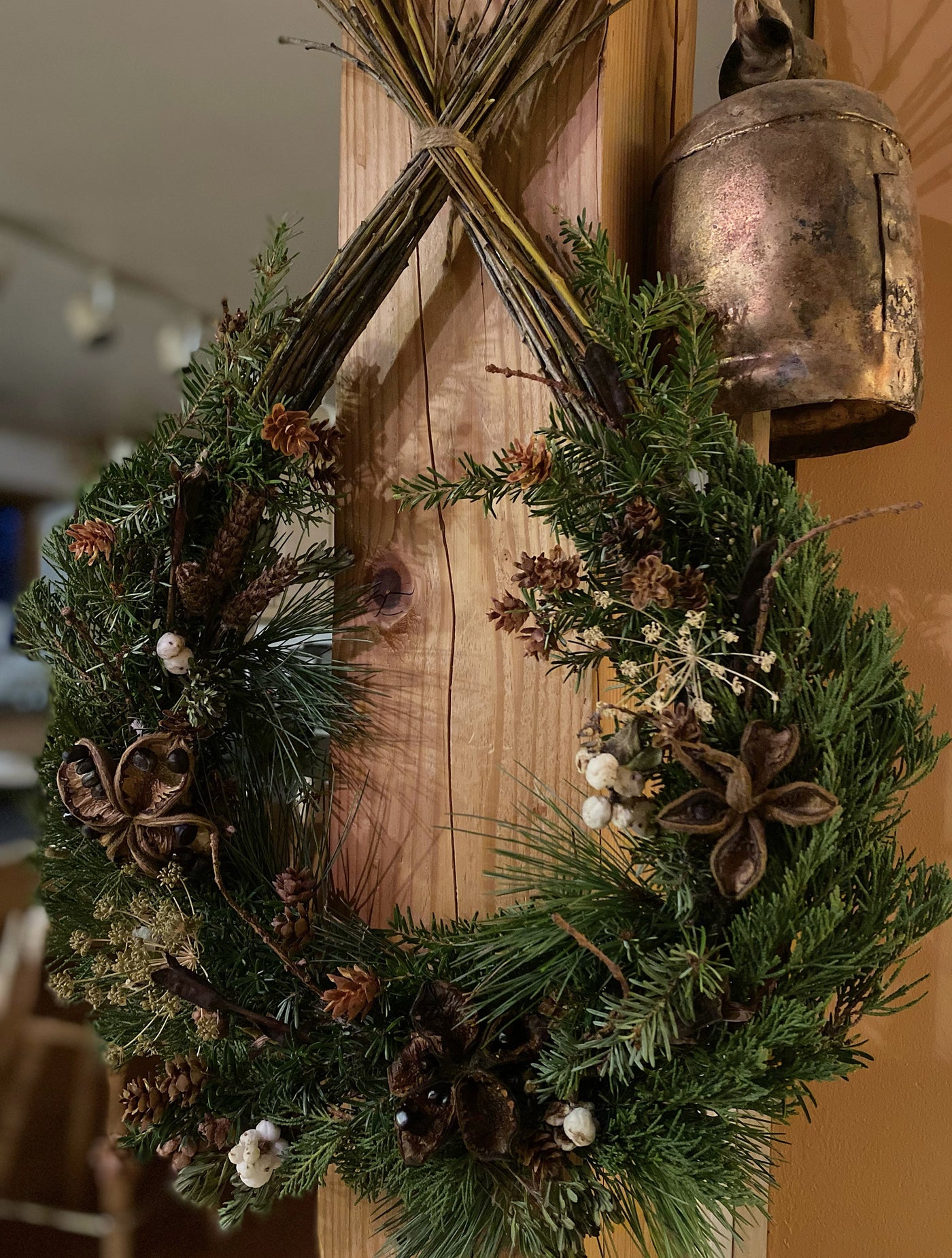 Tear drop shaped holiday wreath made from willow branches and decorated with pine, cedar and hemlock tree branches with dried flowers and seed pods. 